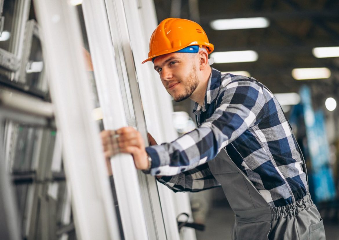 Spécialiste en réparation de volets roulants Un ouvrier souriant inspecte une structure, symbolisant la qualité de la réparation de volets roulants.