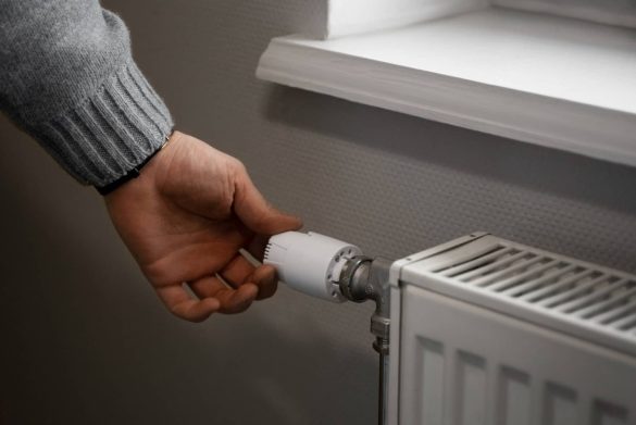 Réglage du radiateur pour une chaudière optimale Gros plan sur une main ajustant le thermostat d'un radiateur, essentiel pour une chaudière efficace.
