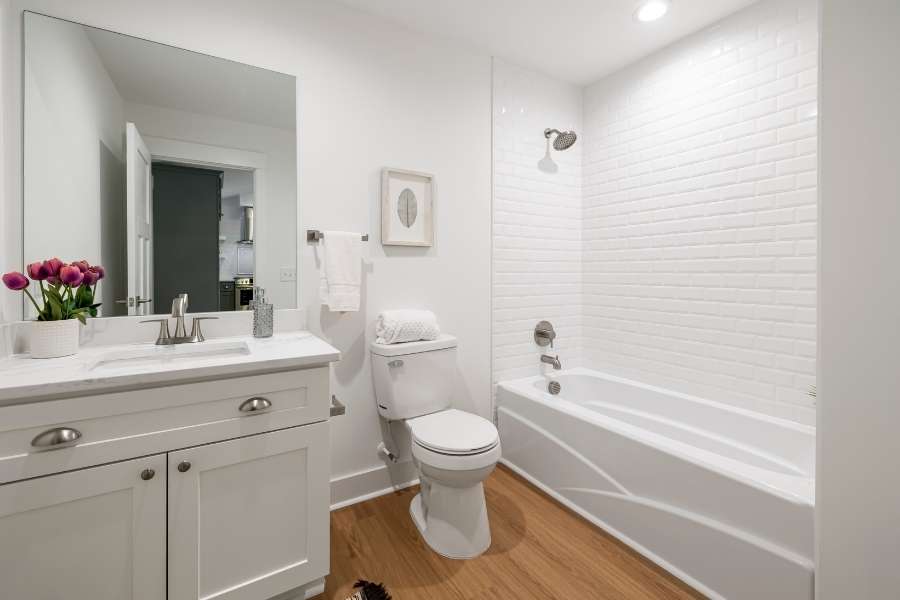 Un meuble de salle de bain blanc classique avec plan de travail en marbre dans une salle de bain lumineuse.