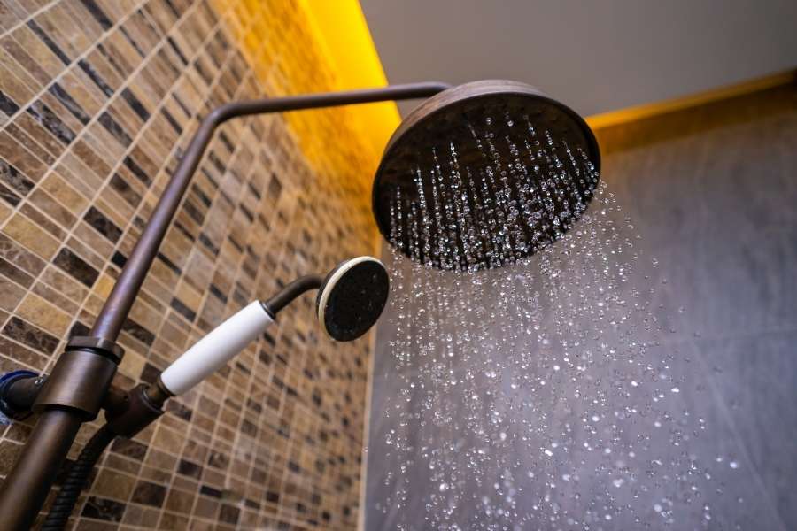 Une douche de tête diffuse de l'eau en pluie dans une salle de bains moderne.