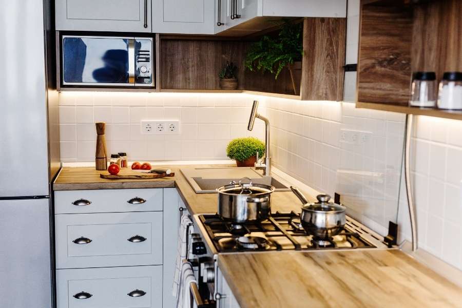 Cuisine moderne avec un plan de travail en bois clair, des casseroles sur une gazinière et des ingrédients frais.
